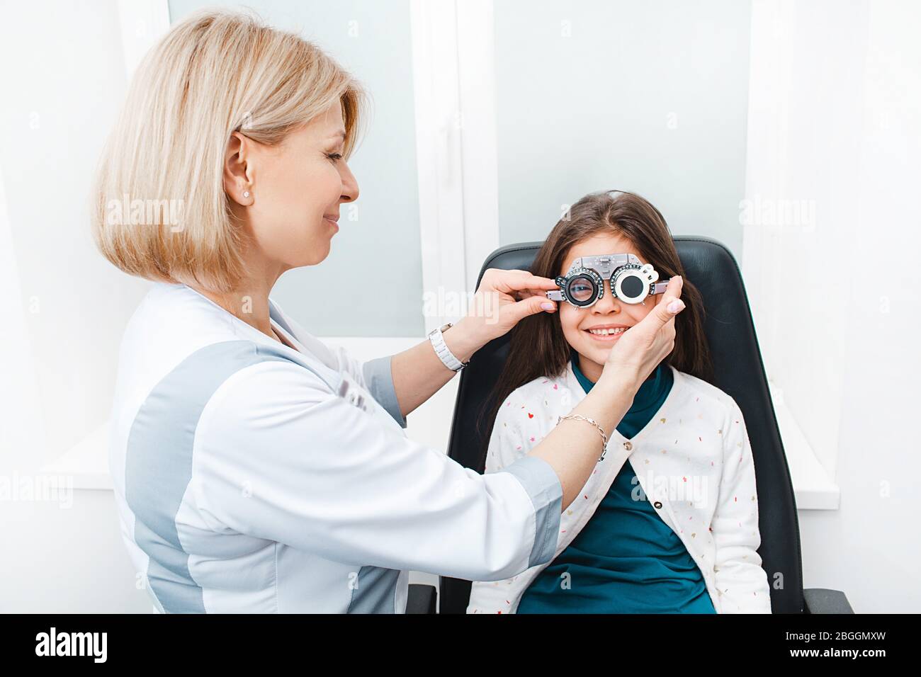 Mixed race Mädchen mit Optometristen Studie Frame in Vision Klinik. Ärztin misst die Sehschärfe Stockfoto