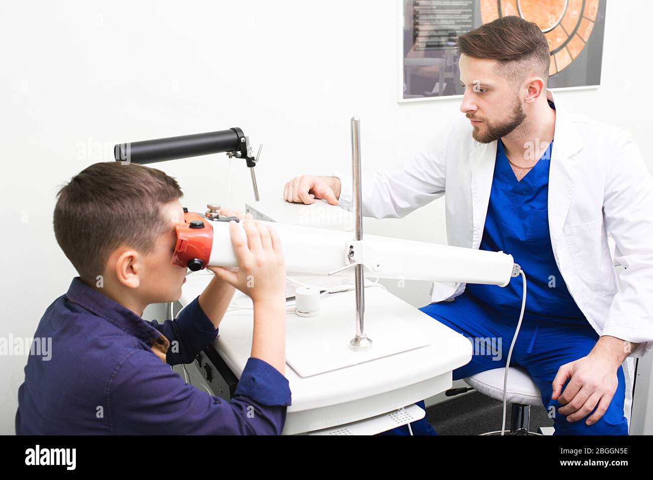 Junge Blick in Gerät, um die Vision zu stimulieren. Augenarzt Überwachung der Behandlung der Sehschärfe mit pleoptischen Methoden. . Augentraining Stockfoto
