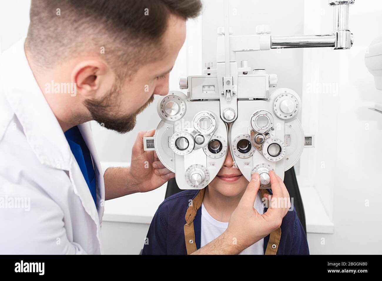 Optometriker Arzt überprüft Teenager Junge Sehvermögen. Wenn der Junge ein schlechtes Sehvermögen hat, wird der Arzt eine Brille verschreiben. Sehkorrektur des Kindes Stockfoto