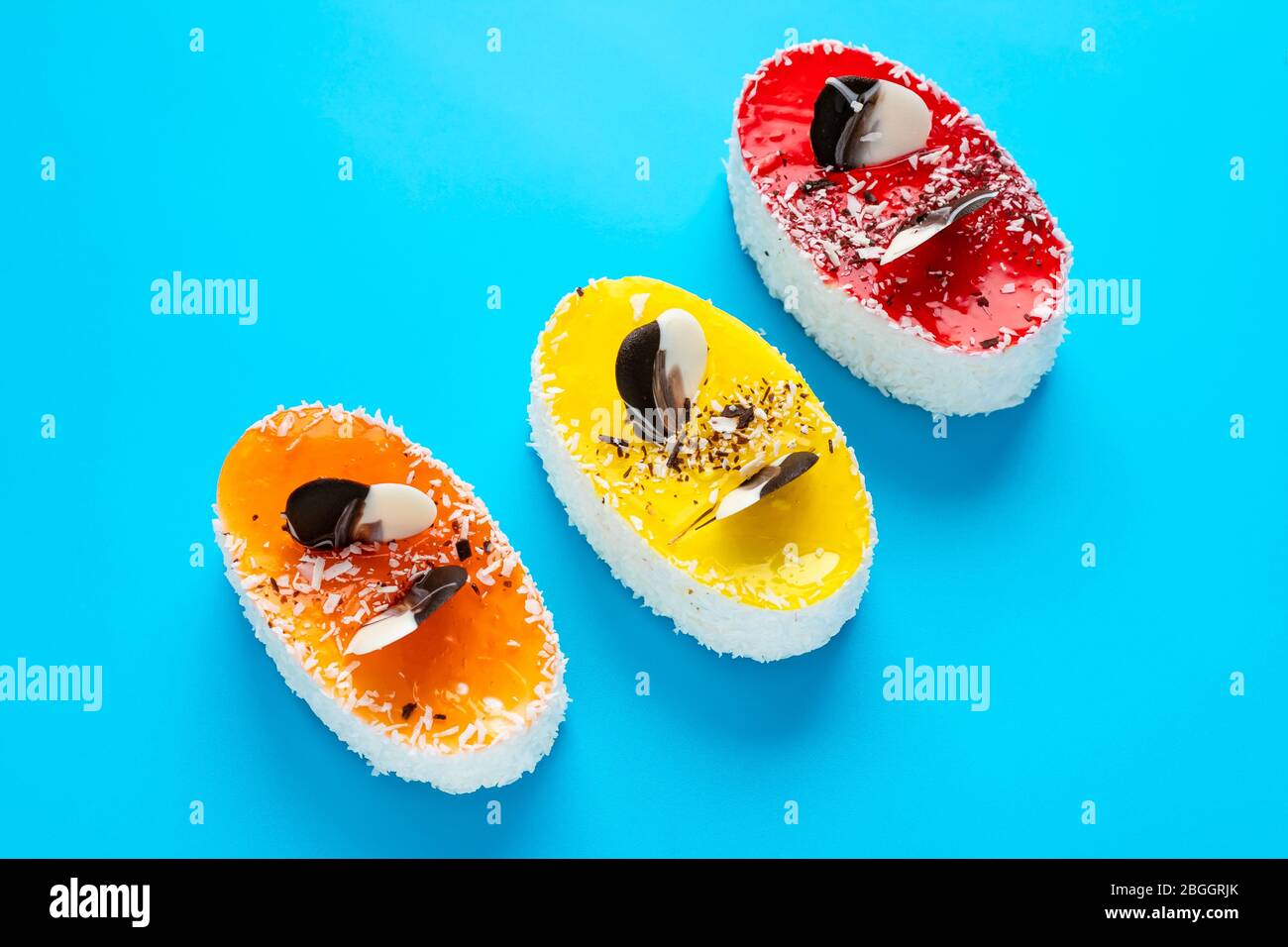 Drei mehrfarbige Kuchen auf hellblauem Hintergrund. Ungesunde Lebensmittel Konzept Stockfoto