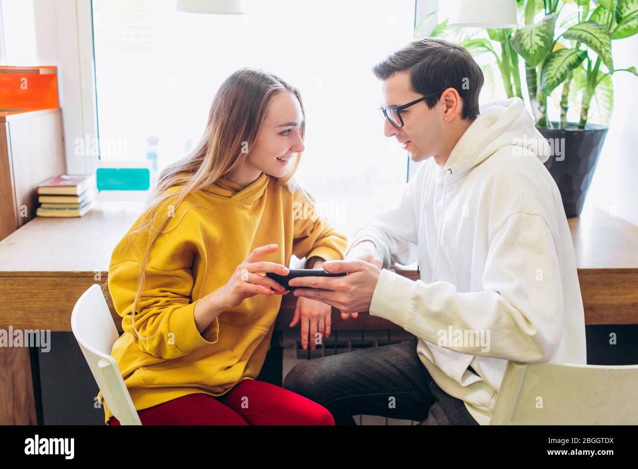 Der Typ und das Mädchen schauen auf das Smartphone und kommunizieren. Stockfoto