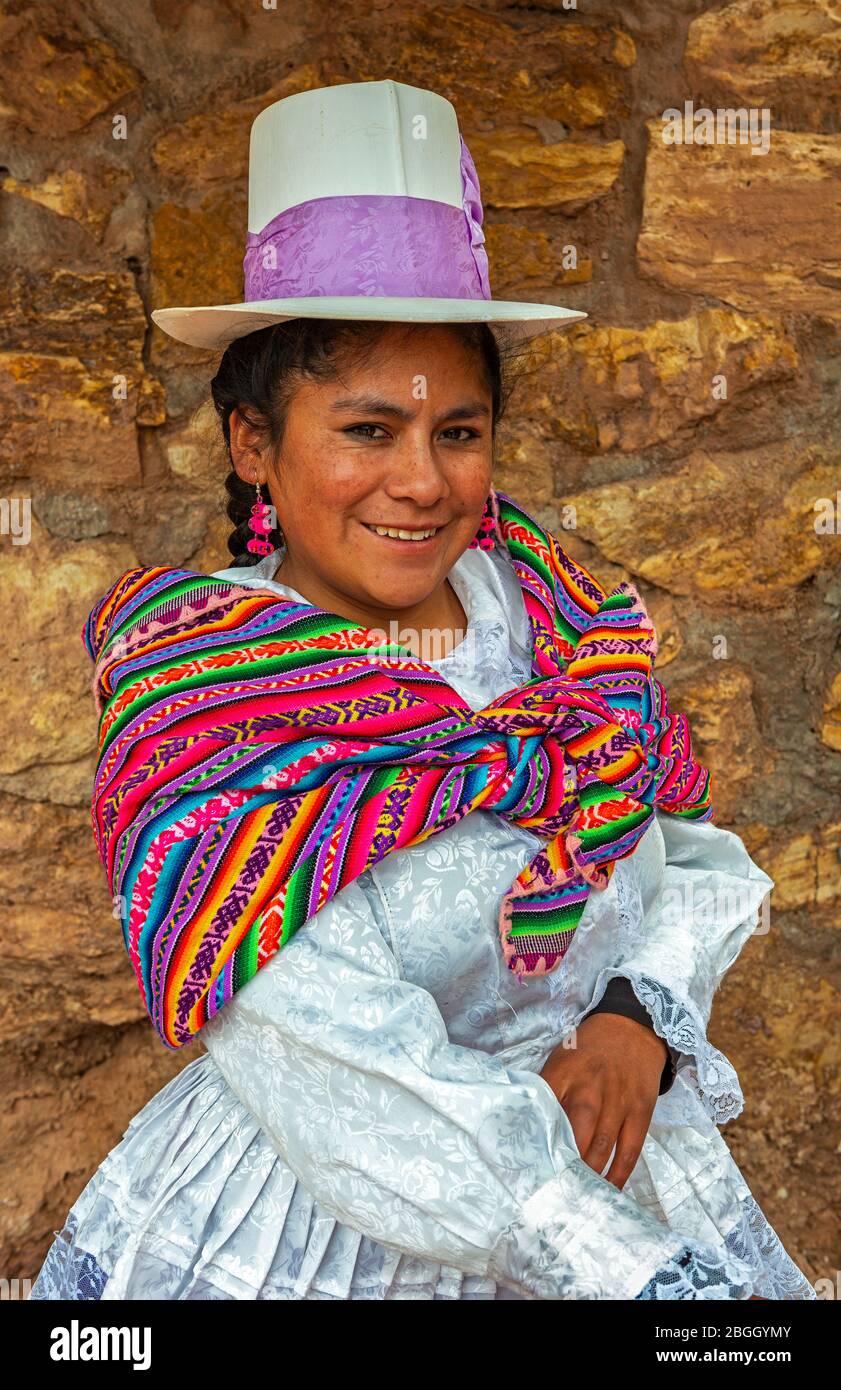 Lächelnde peruanische Quechua-indigene Frau in traditioneller Kleidung der Maras: Weißes Kleid, hoher Hut und Wollschal. Maras, Peru. Stockfoto