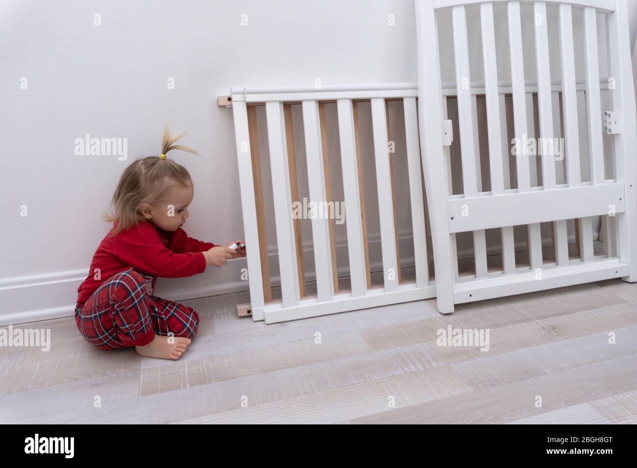 Kleines Kind versucht, das Kinderbett zu reparieren. Stockfoto