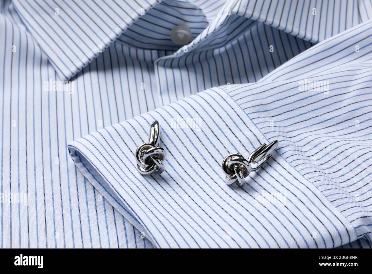 Gestreiftes, weißes und blaues Herrenshirt aus nächster Nähe mit knotförmigen Manschettenknöpfen. Nahaufnahme. Selektiver Fokus. Stockfoto