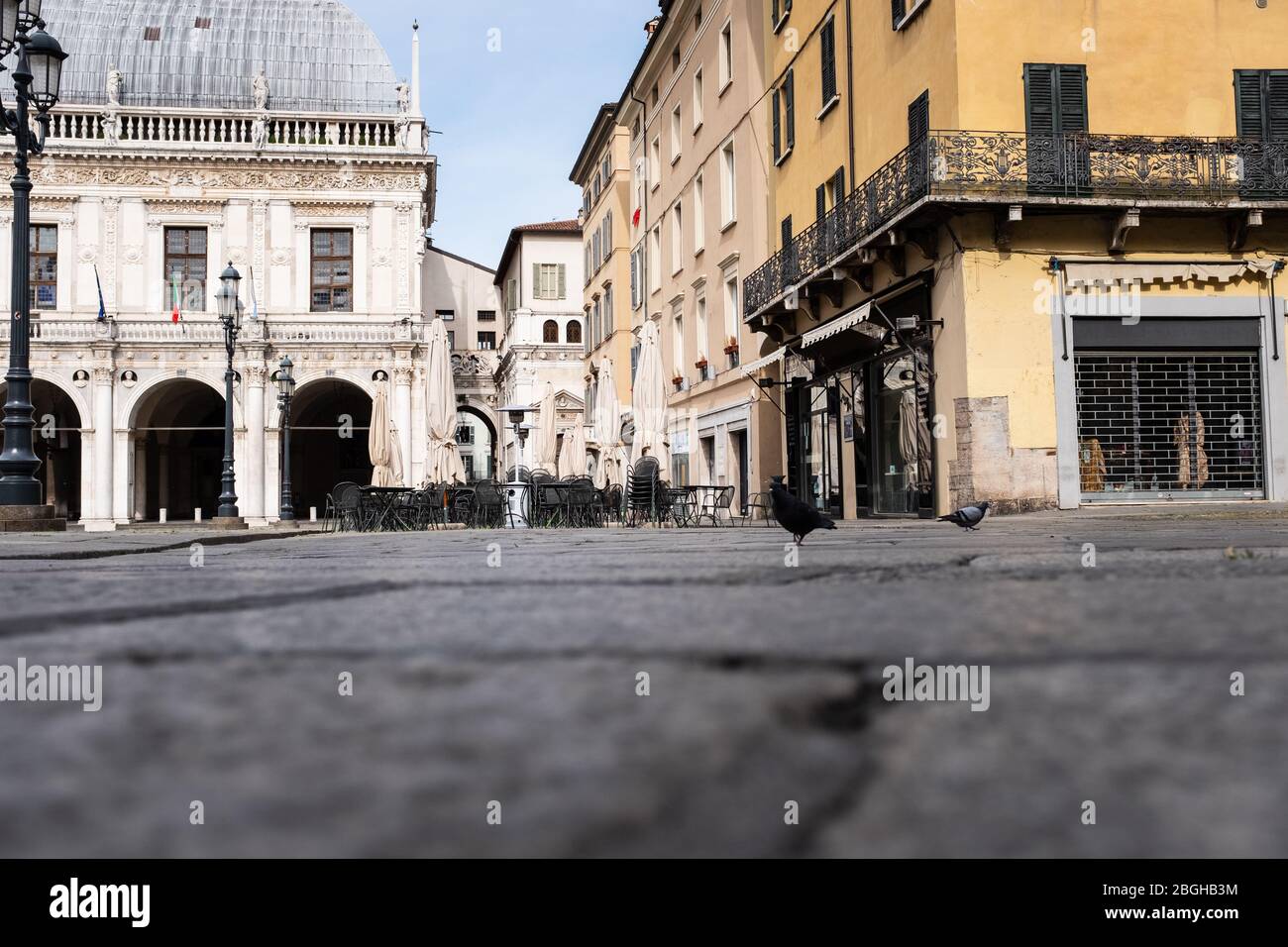 Blick auf die Straße auf einen ungewöhnlich leeren italienischen Platz am Samstagmorgen: Einige Tauben auf der Suche nach Nahrung. Stockfoto