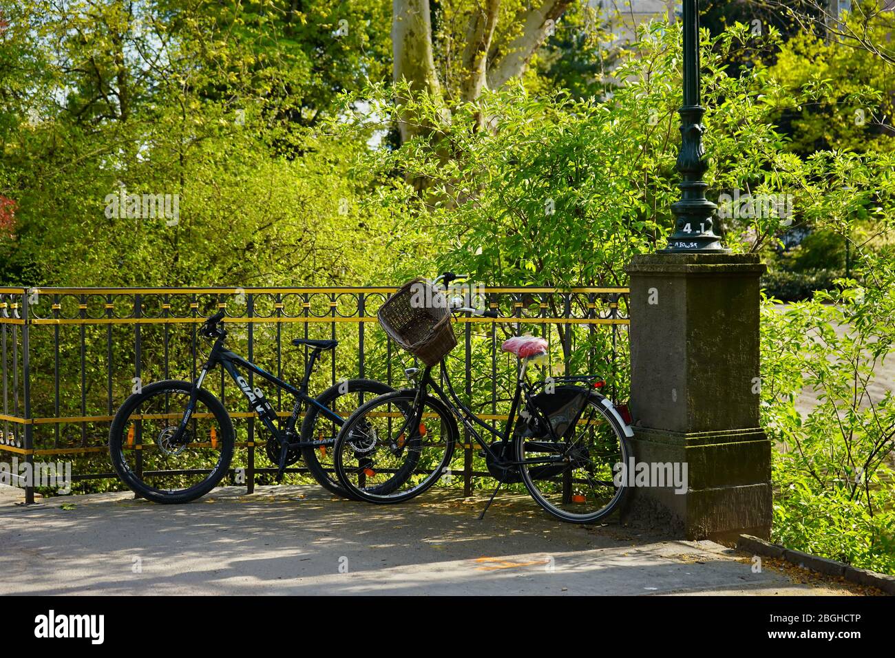 Zwei Fahrräder lehnen sich gegen den Zaun der sogenannten „goldenen Brücke“ im öffentlichen Park „Hofgarten“. Es ist die älteste Fußgängerbrücke der Stadt, erbaut 1853. Stockfoto