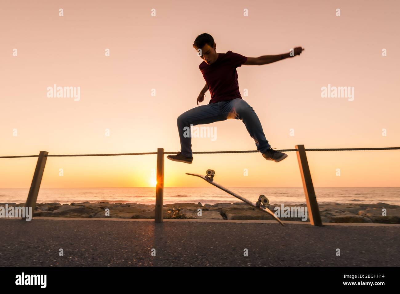 Skater machen Trick Kickflip gegen den schönen orangefarbenen Sonnenuntergang. Stockfoto
