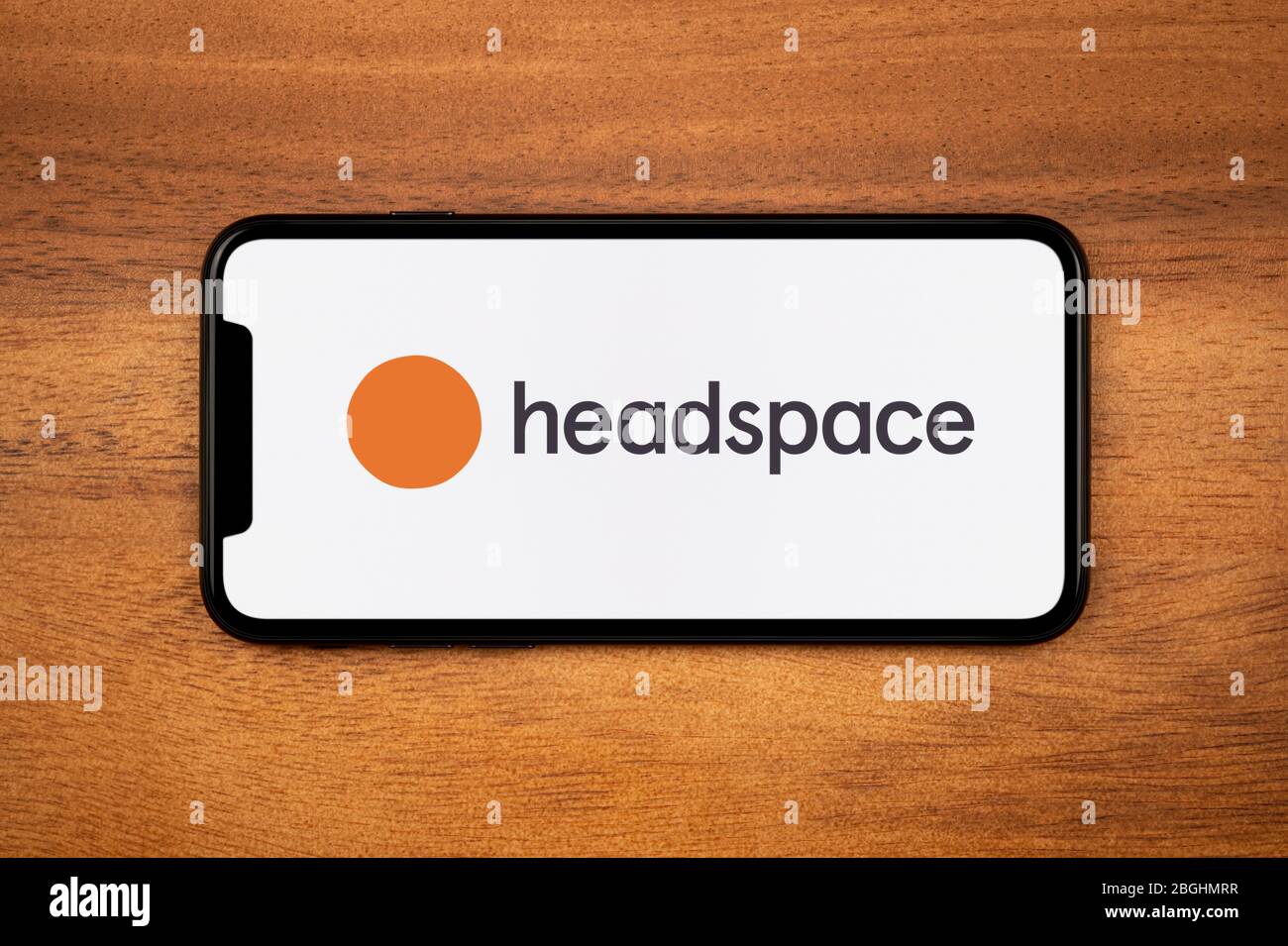 Ein Smartphone mit dem Headspace App Logo liegt auf einem einfachen Holztisch (nur redaktionelle Verwendung). Stockfoto