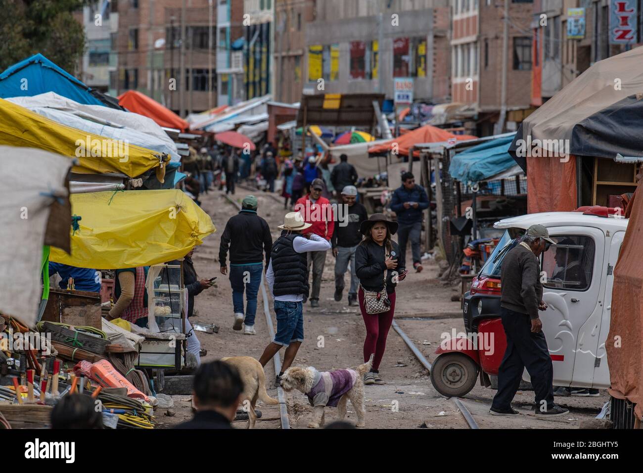 Lokale Menschen gehen über ihre täglichen Geschäfte und überqueren die Bahngleise wie der Zug von Puno nach Cusco passiert Durch Stockfoto