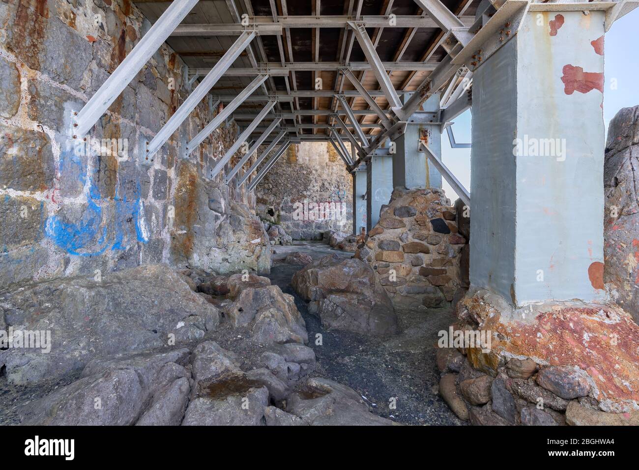 Cefalu, Italien - 24. März 2019: Leerer Durchgang und metallische Gebäudestruktur unter den Häusern auf Felsen an der Küste gebaut. Stockfoto