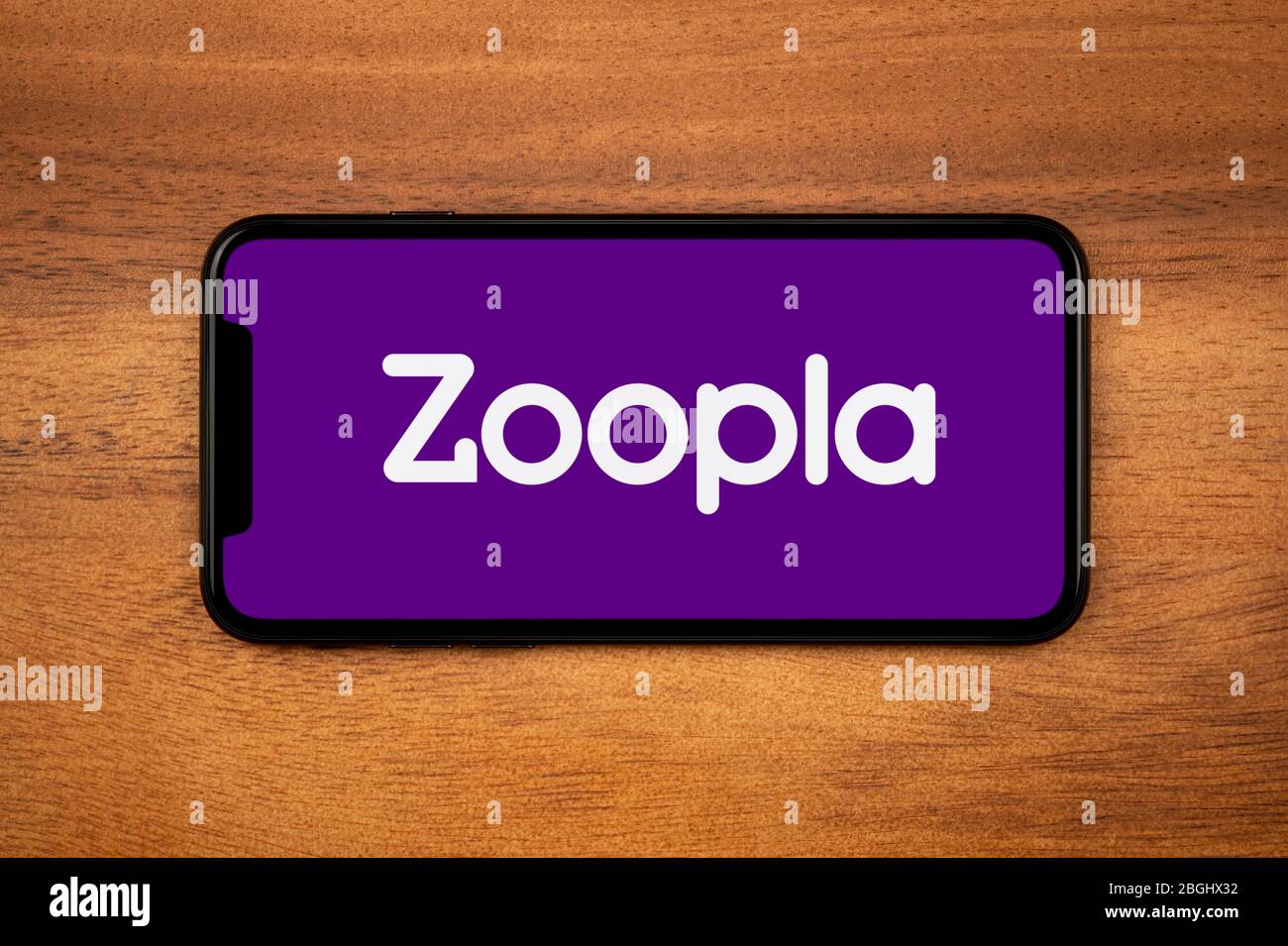 Ein Smartphone mit dem Zoopla-Logo liegt auf einem einfachen Holztisch (nur für redaktionelle Verwendung). Stockfoto