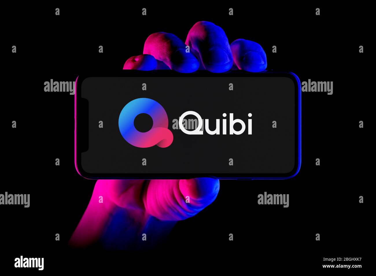 Ein Smartphone mit dem Quibi App Logo wird von einer Handaufnahme auf schwarzem Hintergrund gehalten (nur redaktionelle Verwendung). Stockfoto