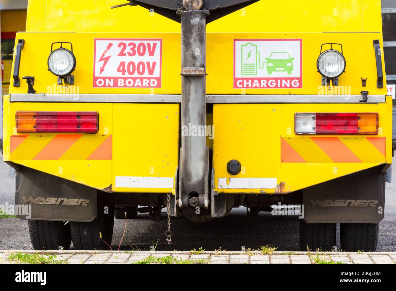 Gelbe Abschleppwagen Rückansicht mit 230V 400V an Bord Schild und Elektroauto Ladeschild, Ungarn, Europa Stockfoto