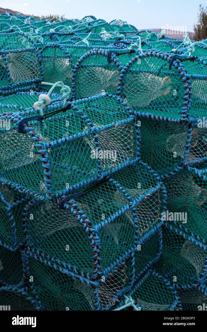 Stapel von blauen schottischen Krabbenköpfen oder Kreellen, die zum Einfangen von Krabben verwendet werden, auf einem Dock auf der Isle of Mull, Schottland. Alte Kreel Fischerei Tradition.Marine Industrie. Stockfoto