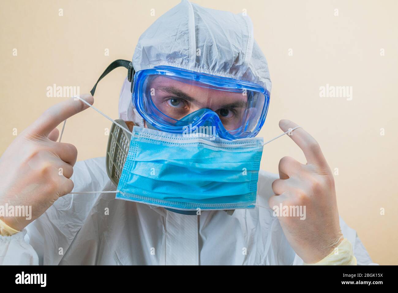 Medizinische Maske in Arzthand in grünem Anzug auf dem glatten gelben Hintergrund. Medizinisches Konzept. Stockfoto