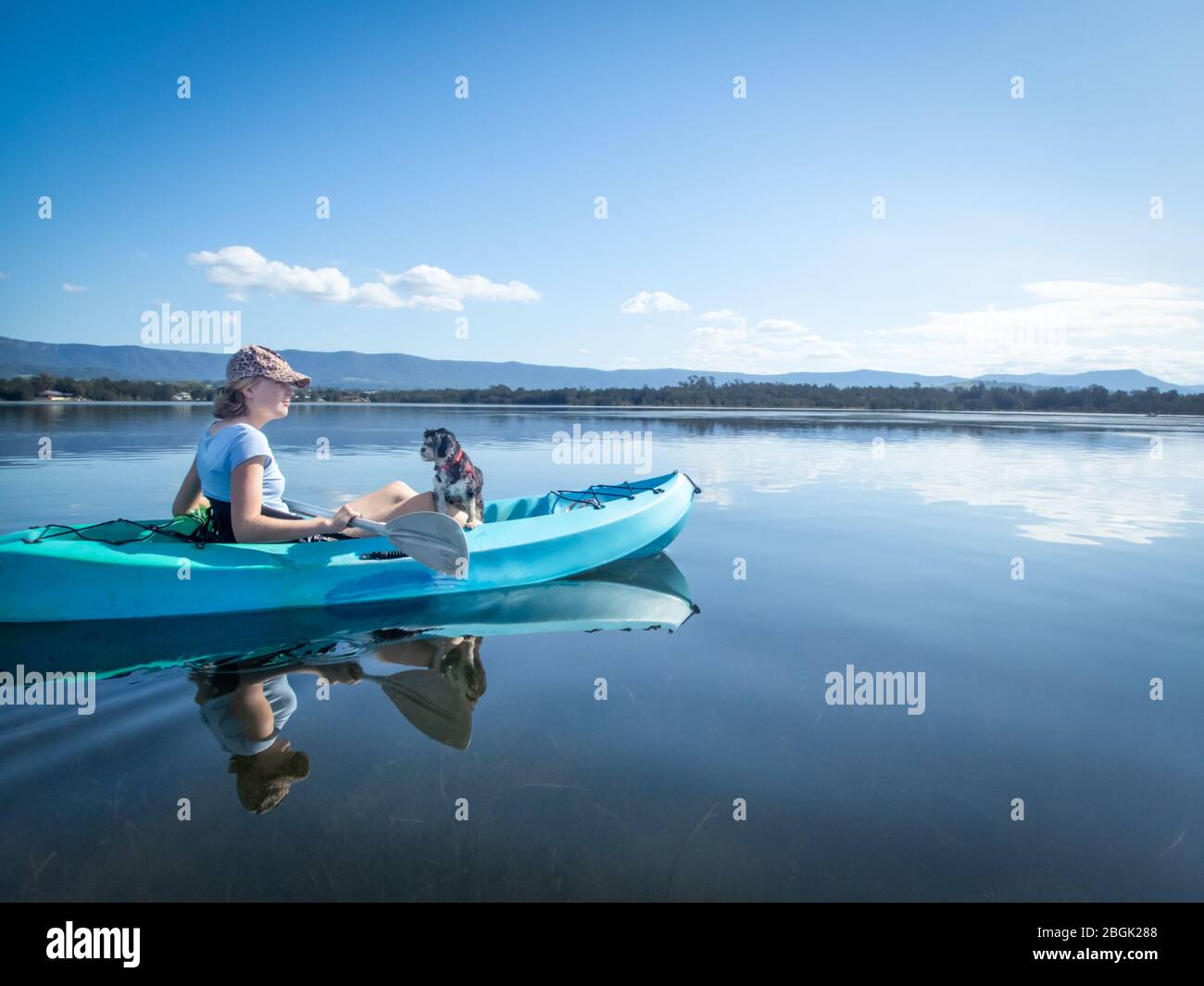 Junge Frau und Hund Kajak auf ruhigen sonnigen See, beste Freunde, Isolation Ruhe und Frieden Konzept Stockfoto
