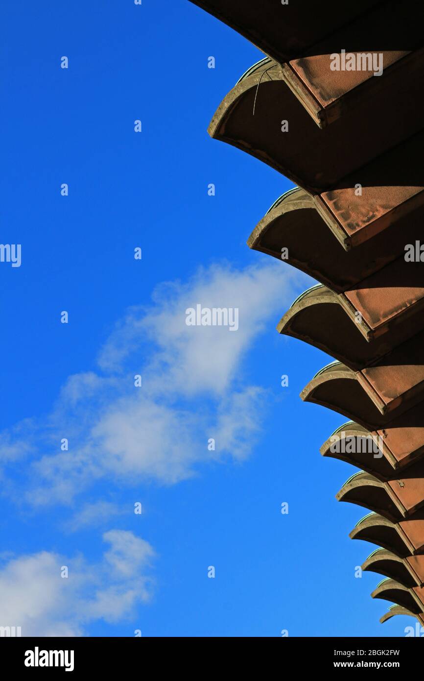Dachrinnen eines Gebäudes mit einem einzigartigen Design, das lebendig in den klaren blauen Himmel leuchtet Stockfoto