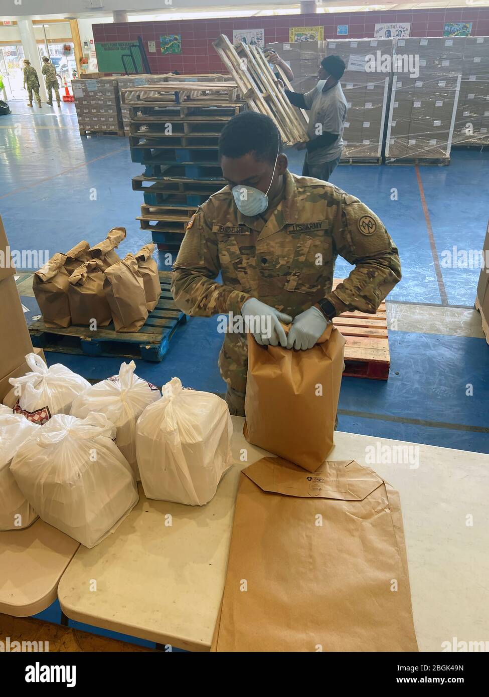 New York Army National Guard Spc. Standley Jean Baptiste, dem 1. Bataillon, 258. Feldartillerie, Teil des 27. Kampfteams der Infanterie-Brigade, zugewiesen, verpackt Mahlzeiten am Lebensmittelverteilungsort Bronx im Hunts Point Recreation Centre 6. April 2020. Die Mahlzeiten werden später an Bürger verteilt, die unter Quarantäne stehen und ihre Häuser nicht verlassen können. Die Nationalgarde hat in der ganzen Stadt mehr als 337,358 Mahlzeiten geliefert. Die Soldaten sind Teil einer landesweiten Anstrengung von mehr als 2,800 Mitgliedern der New York National Guard, die auf die Bedürfnisse der Gemeinschaft reagieren, um die Auswirkungen zu mildern Stockfoto