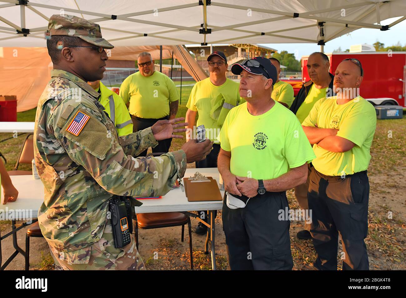 Lake Charles Resident Capt. Julian Green (links), Kommandeur der Louisiana National Guard's Headquarters und Headquarters Company, 2. Bataillon, 256th Infantry Brigade Combat Team, Weist die freiwilligen Feuerwehrleute von Bridge City an, wie man ein Thermometer zur Tierarzt- und Rettungsdienst-Untersuchung in einem mobilen COVID-19-Testzentrum im Alario-Zentrum in Westwego, Louisiana, 21. März 2020, verwendet. (USA Foto der Armee-Nationalgarde von Staff Sgt. Garrett L. Dipuma) Stockfoto