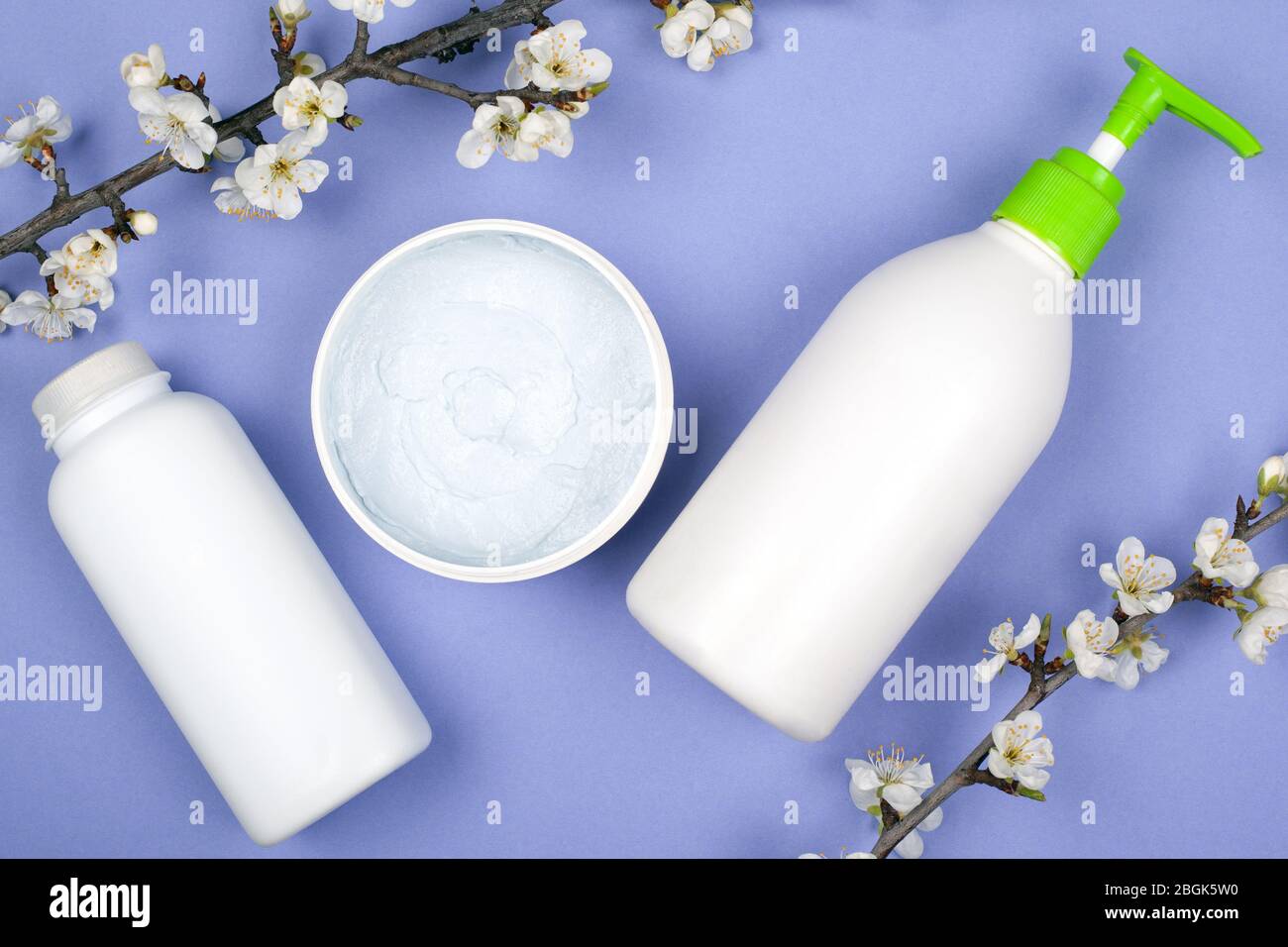 Weiße Flaschen mit Kosmetik blühenden Frühling Aprikosen Zweige kopieren Raum auf lila Hintergrund. Schönheit. Stockfoto