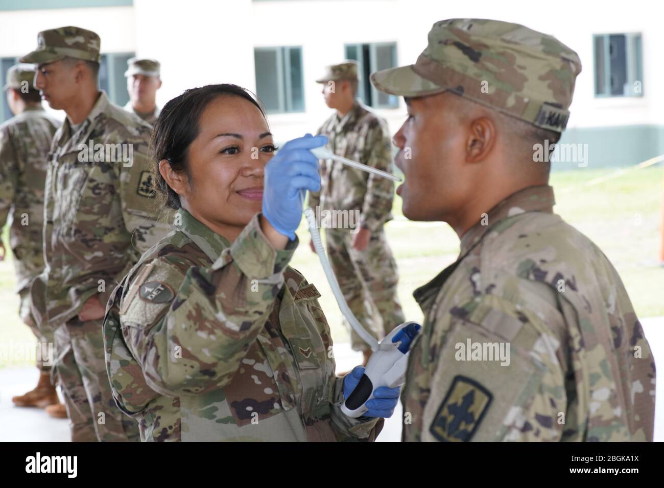 Air Men 1st Class Jolene Chun, Medical Detachment 1, Hawaii Air National Guard, nimmt die Temperatur eines Soldaten für seine tägliche medizinische Beurteilung, 24. März 2020, Honolulu Hawaii. Mitglieder der Task Force "Hawaii National Guard COVID-19" werden täglich medizinisch gescreent, um sicherzustellen, dass der Soldat oder die Flieger nicht COVID-19 ausgesetzt wurden oder Symptome zeigen. (USA Air National Guard Foto Von Tech. Sgt. Andrew Lee Jackson) Stockfoto