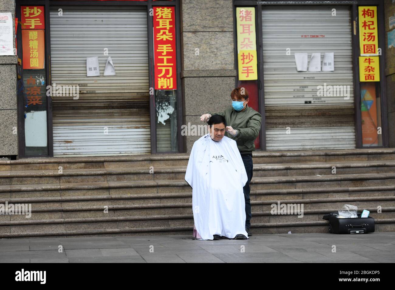 Ein Friseur macht Haarschnitt für eine Person auf der Straße im Yubei Bezirk im Südwesten Chinas Chongqing, 4. März 2020. Stockfoto