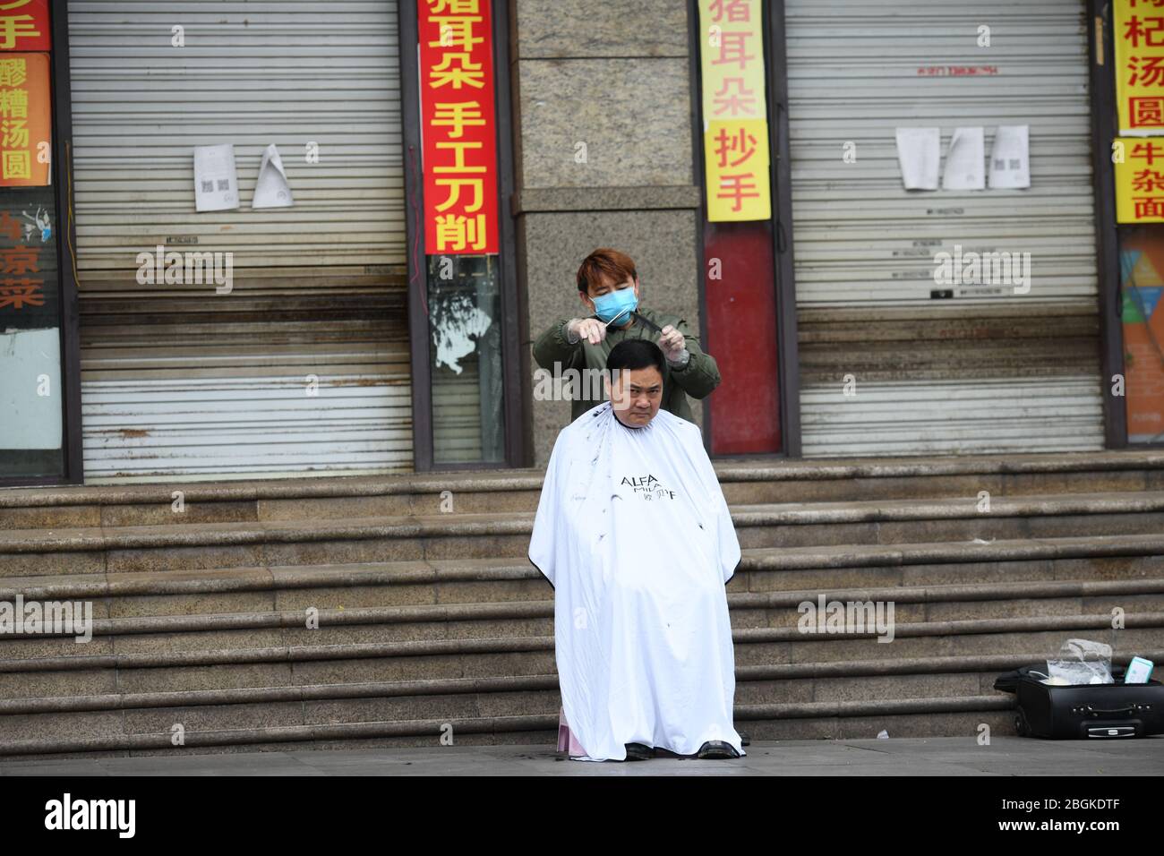 Ein Friseur macht Haarschnitt für eine Person auf der Straße im Yubei Bezirk im Südwesten Chinas Chongqing, 4. März 2020. Stockfoto