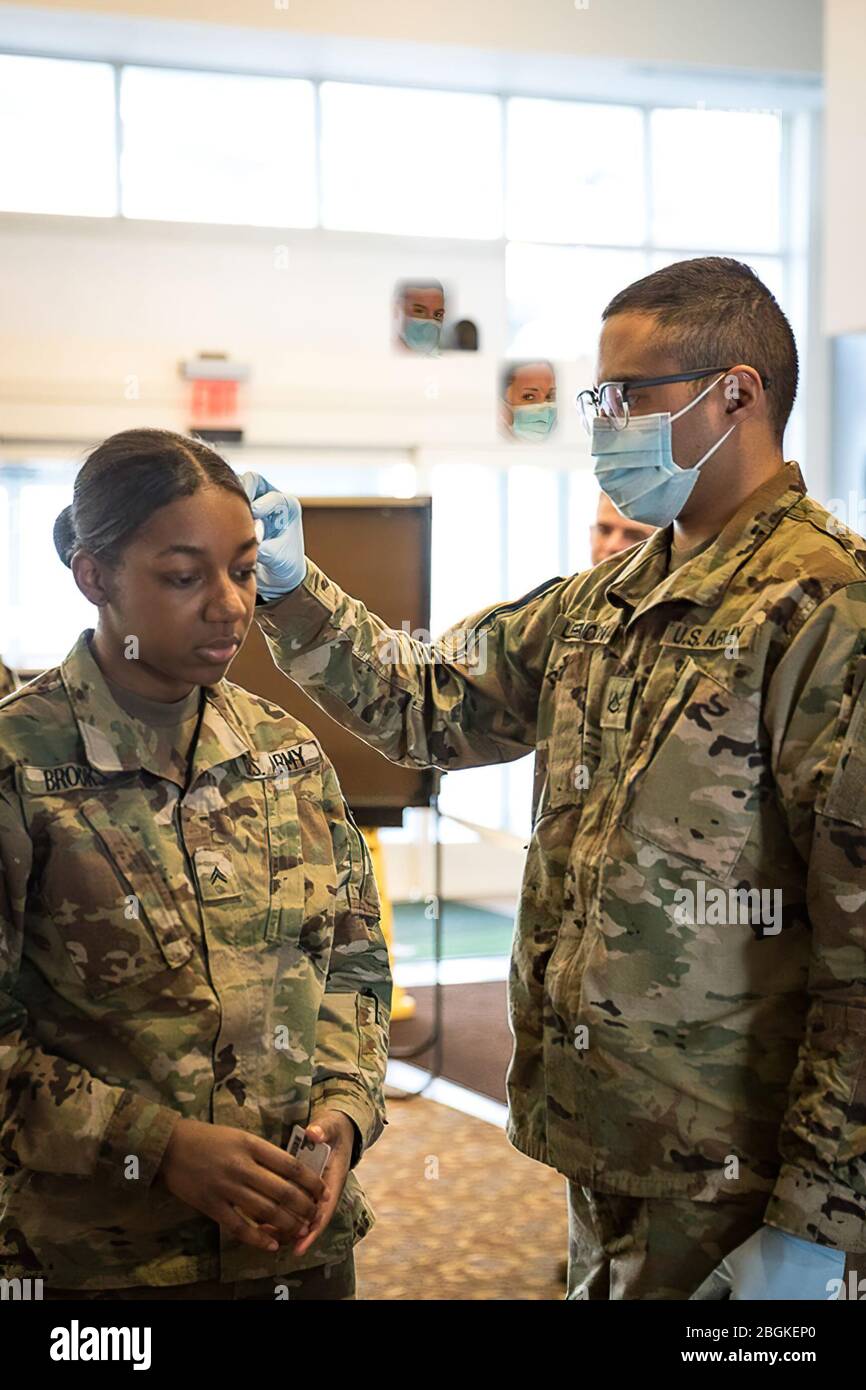 Pfc Nicholas Leemoon, 1171st Medical Company Area Support, führt ein medizinisches Screening auf CPL durch. Catherine Brooks, 156. Expeditionary Signal Battalion, um das Risiko von COVID-19 in Romulus, Michigan, am 6. April 2020 zu verringern. Die Michigan National Guard ist hier, um den Gemeinden zu dienen; sie sind Nachbarn und Partner in diesen schwierigen Zeiten. (Foto der Armee-Nationalgarde von 2. LT. Ashley Goodwin) Stockfoto