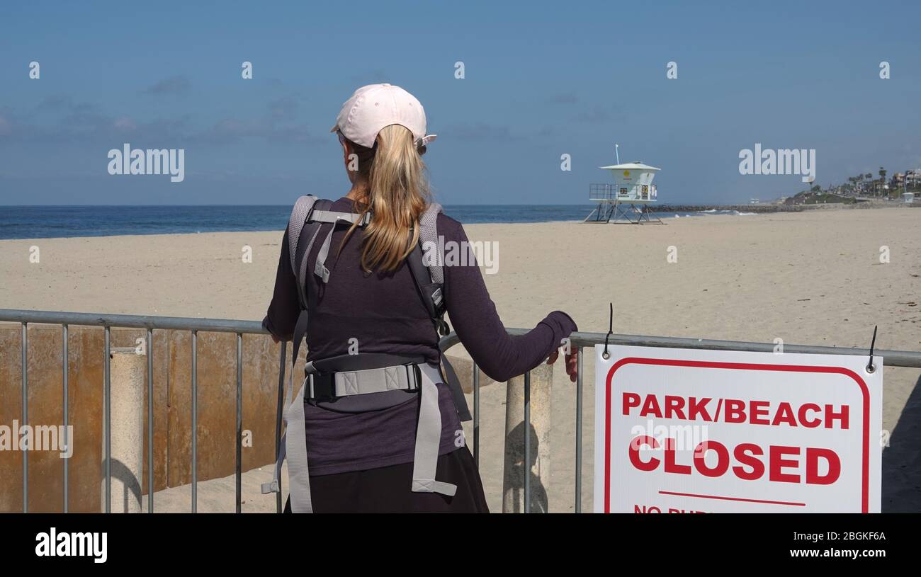 Eine Frau blickt auf den menschenleeren Strand, der wegen der Covid-19-Beschränkungen geschlossen wurde. Stockfoto