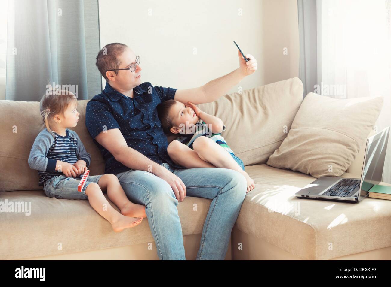 Vater und seine Kinder sprechen online per Telefon mit Verwandten oder Freunden. Online-Kommunikation, Fernkommunikation. Stockfoto