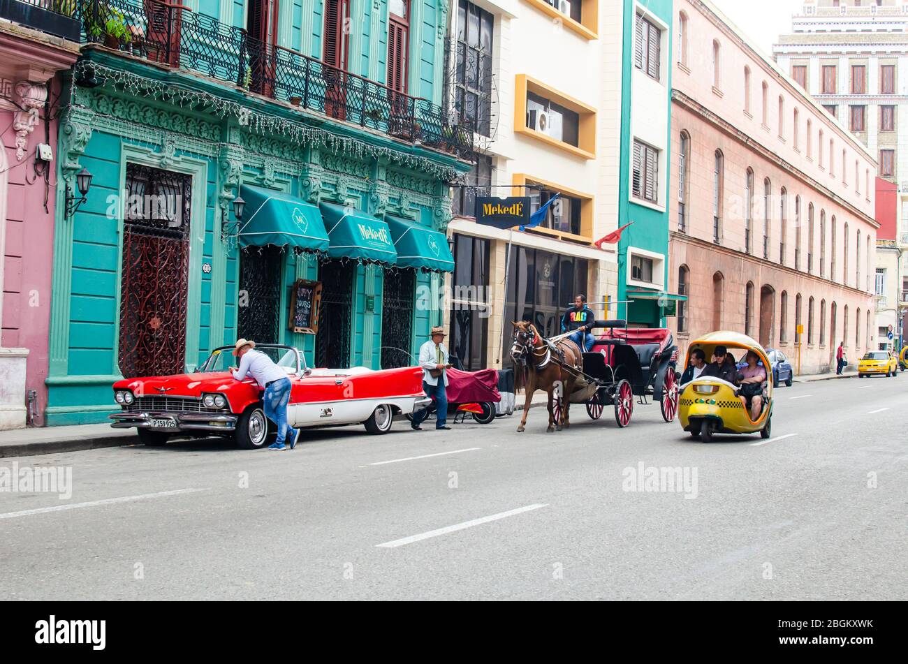 Fesselnde Momentaufnahme der Altstadt von Havanna mit einem Oldtimer, einem Cocotaxi und einer Pferdekutsche, die die berühmte Szene definiert. Stockfoto