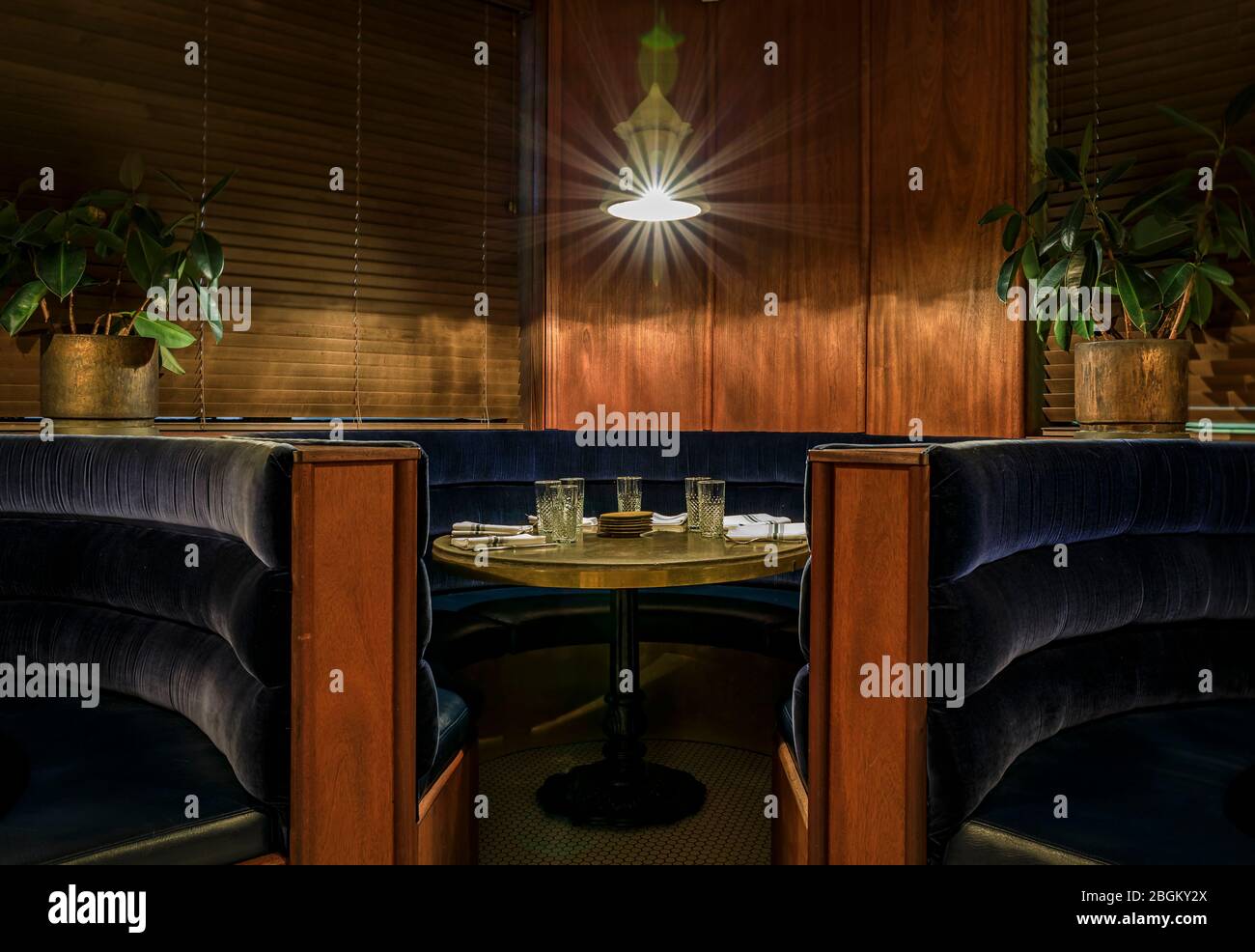 Sitzgruppe und Tisch im Art-Deco-Stil aus Samt in einem Raum mit Holztäfelung an den Wänden und Vintage-Leuchte mit Lichteffekt Stockfoto