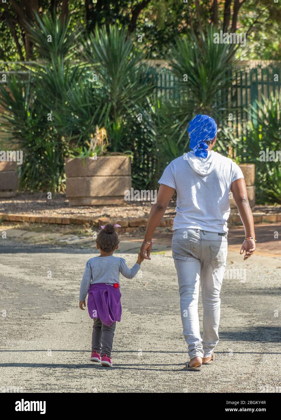 Alberton, Südafrika - nicht identifizierter Vater und kleine Tochter gehen Hand in Hand das Straßenbild im vertikalen Format hinunter Stockfoto