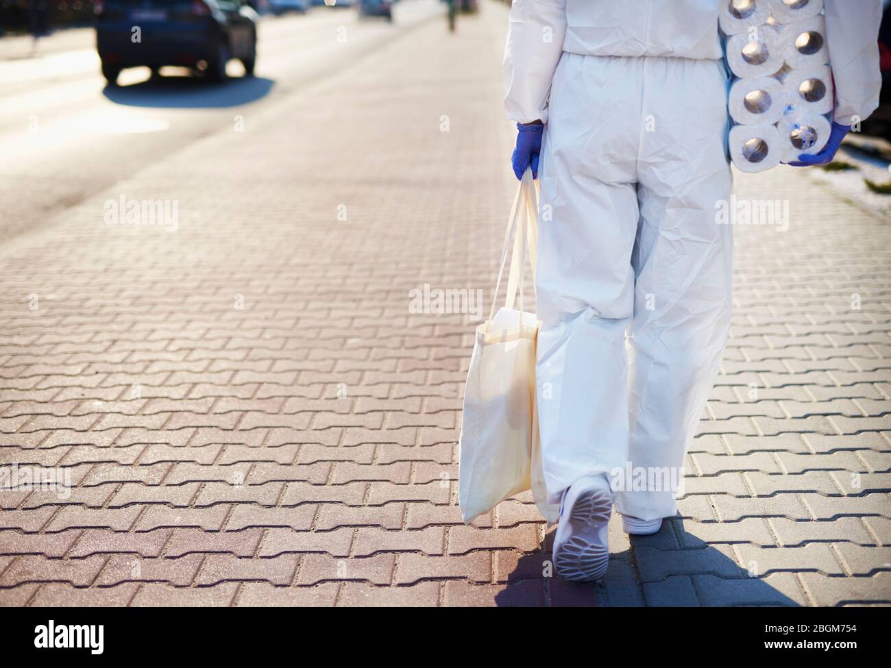 Person in Schutzanzug, die vom Einkaufen zurückkehrt Stockfoto