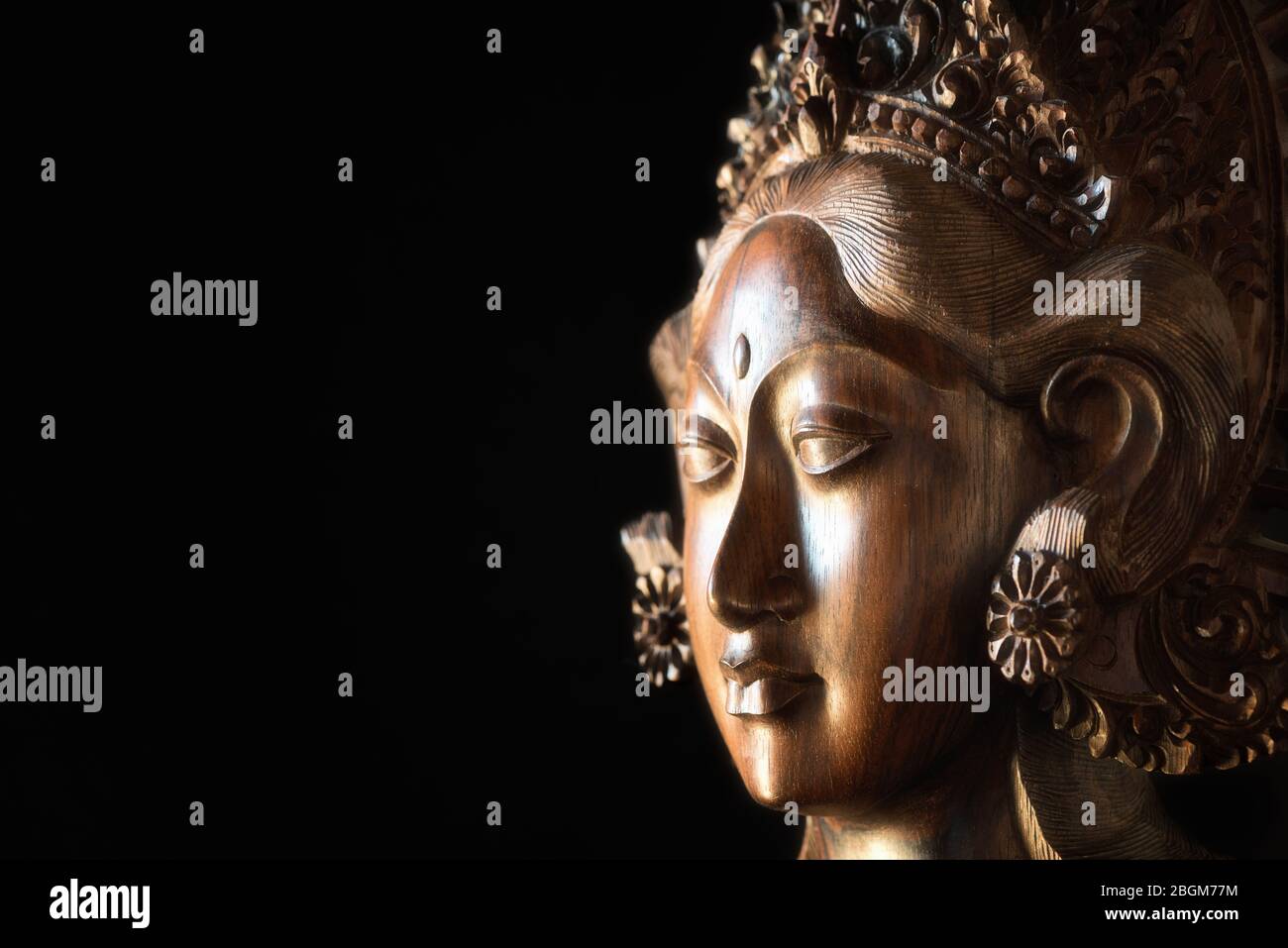 Geschnitzter weiblicher Kopf aus Holz. Parvati Gesicht, hinduistische Göttin der Fruchtbarkeit, Liebe, Schönheit, Ehe, Kinder und Hingabe. Balinesische Handarbeit. Stockfoto