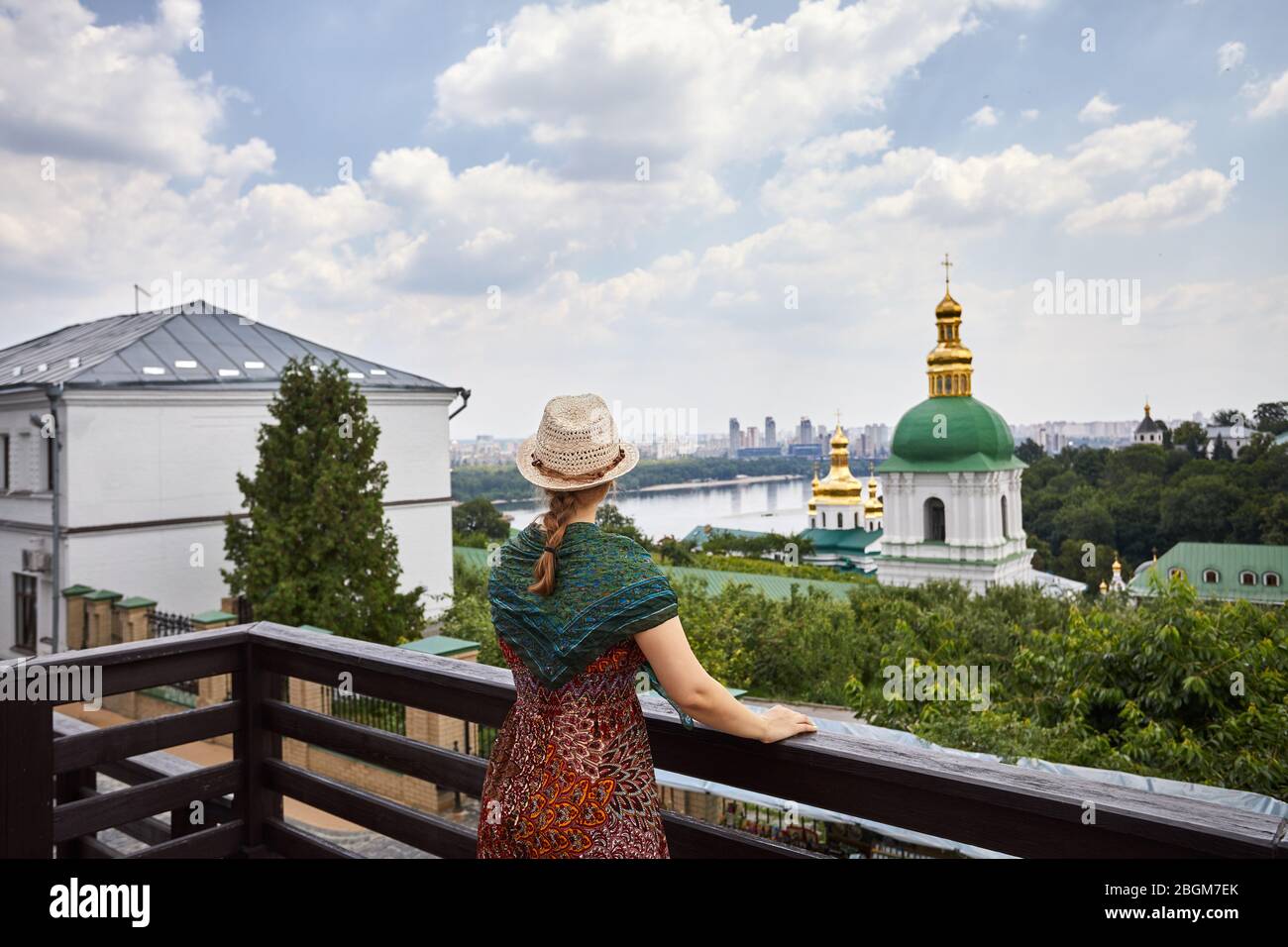 Frau mit Hut mit Schal mit Blick auf die Kirche mit goldenen Kuppeln in Kiew Pechersk Lavra Christian komplex. Alte historische Architektur in Kiew, Ukraine Stockfoto
