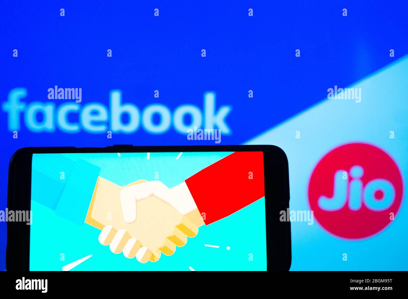 Handy mit Handshake-Bildschirm und facebook und jio im Hintergrund Stockfoto