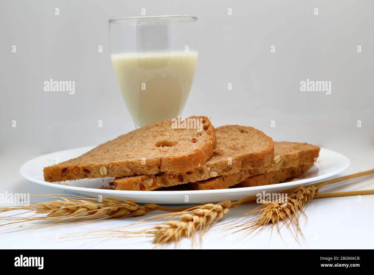 Frisches Brot mit Milchglas in einem Keramikplatte. Stockfoto