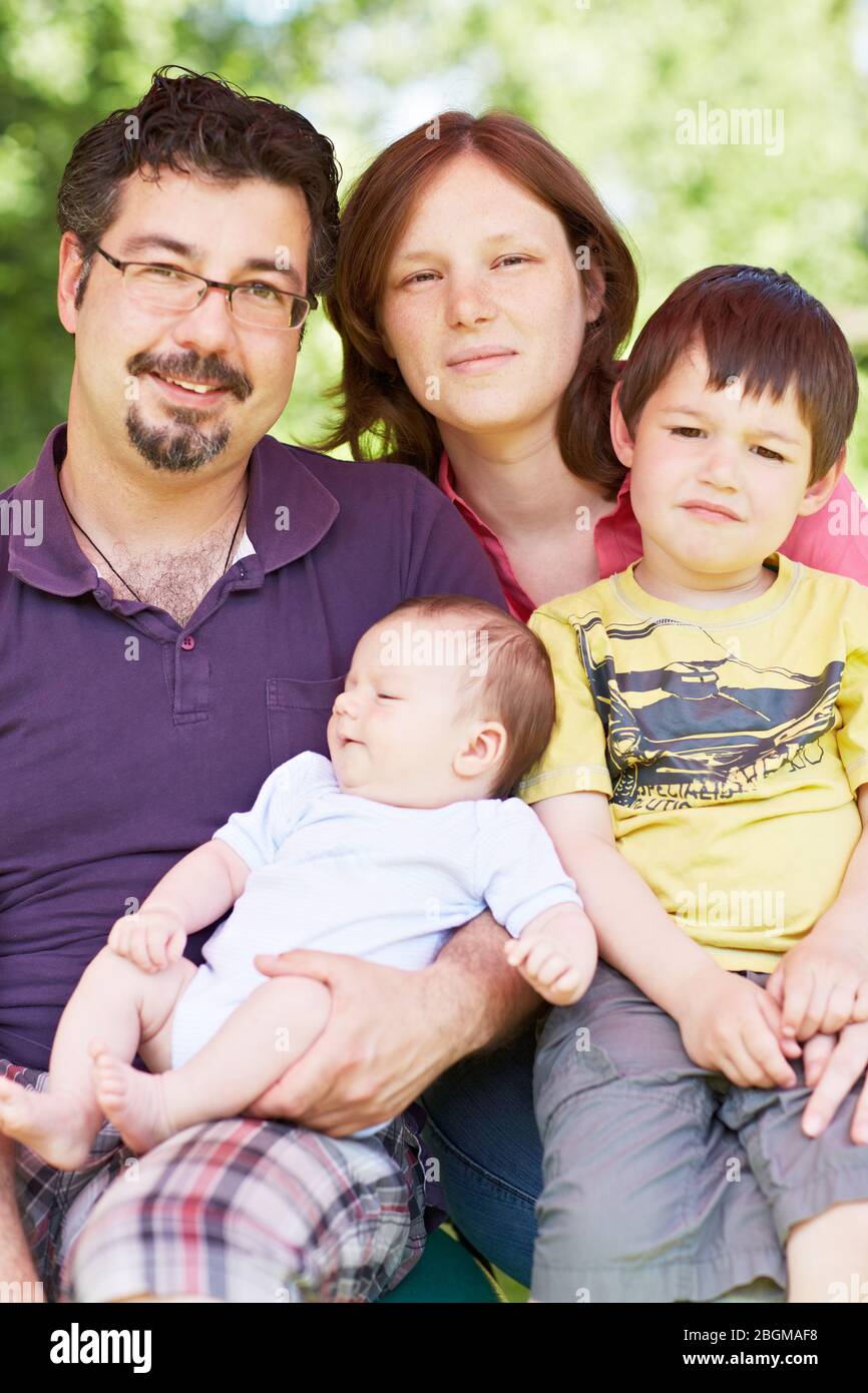 Glückliche Familie mit Kind und Baby sitzt im Freien Stockfoto