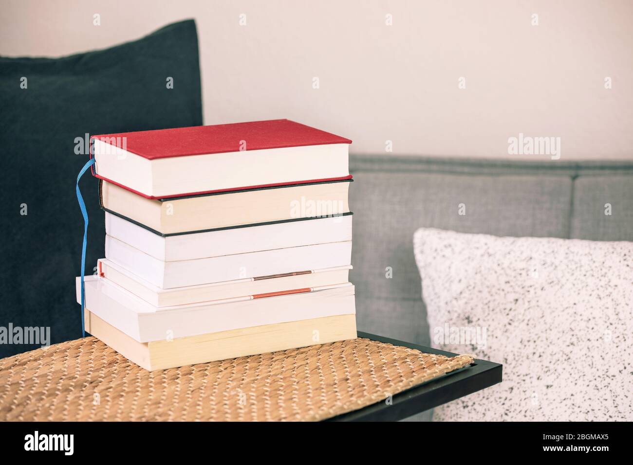 Bücherstapel auf dem Tisch mit gemütlichem Sofa, Kissen und Kissen. Bücher lesen, zu Hause lernen, lernen. Stockfoto