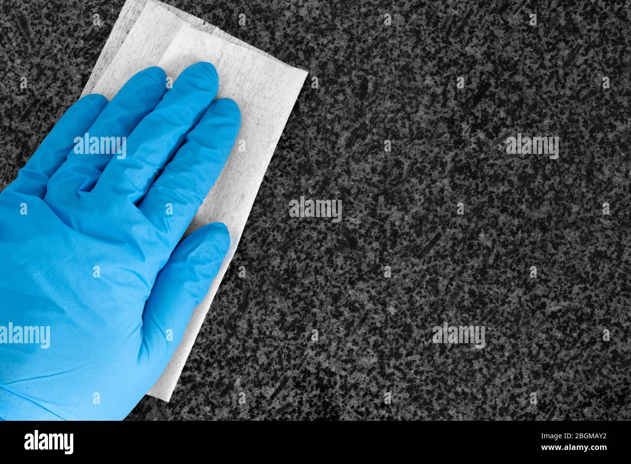 Person, die Handschuhe trägt, reinigt Arbeitsplatte aus Granit mit einem antibakteriellen Wischtuch. Tötung von Bakterien und Keimen Konzept Stockfoto