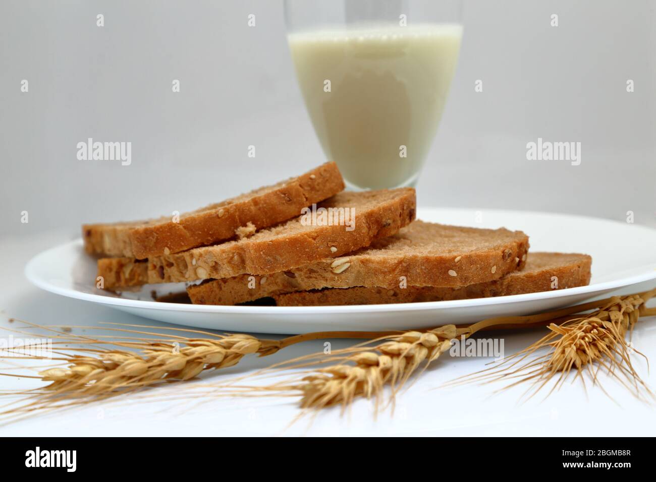 Frisches Brot mit Milchglas in einem Keramikplatte. Stockfoto