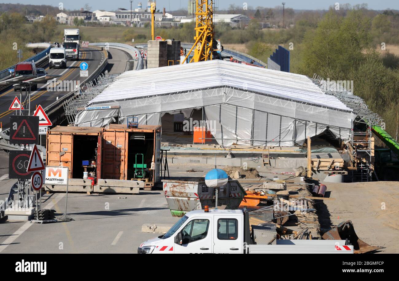 Tribsees, Deutschland. April 2020. Der erste neu gebaute Brückenabschnitt auf der versunkenen Ostseestrecke A20 ist mit Kunststoffplanen überzogen und soll im Juni fertiggestellt werden. Der Verkehr fließt auf der linken Seite vorbei. Nun beginnt der Bau des westlichen Brückenabschnitts in Richtung Rostock. Nach dem Bau der Baustraßen werden die Bohrgeräte im Juni eintreffen, um die bis zu 25 Meter langen 332 Fundamentpfähle zu platzieren. Bis Ende 2021 soll die Rostocker Fahrtrichtung komplett fertig sein. Quelle: Bernd Wüstneck/dpa-Zentralbild/dpa/Alamy Live News Stockfoto