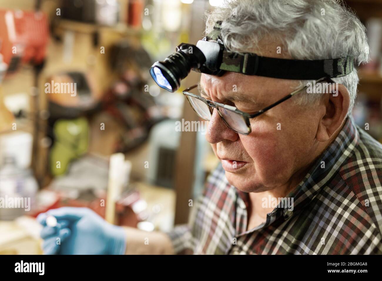 Hochrangiger Handwerker Porträt mit Stirnlampe LED Taschenlampe Arbeiten im  Arbeitsgang mit Werkzeugen und Ausrüstung im Hintergrund. Alter reifer  grauer Hauslehrer mit Stockfotografie - Alamy