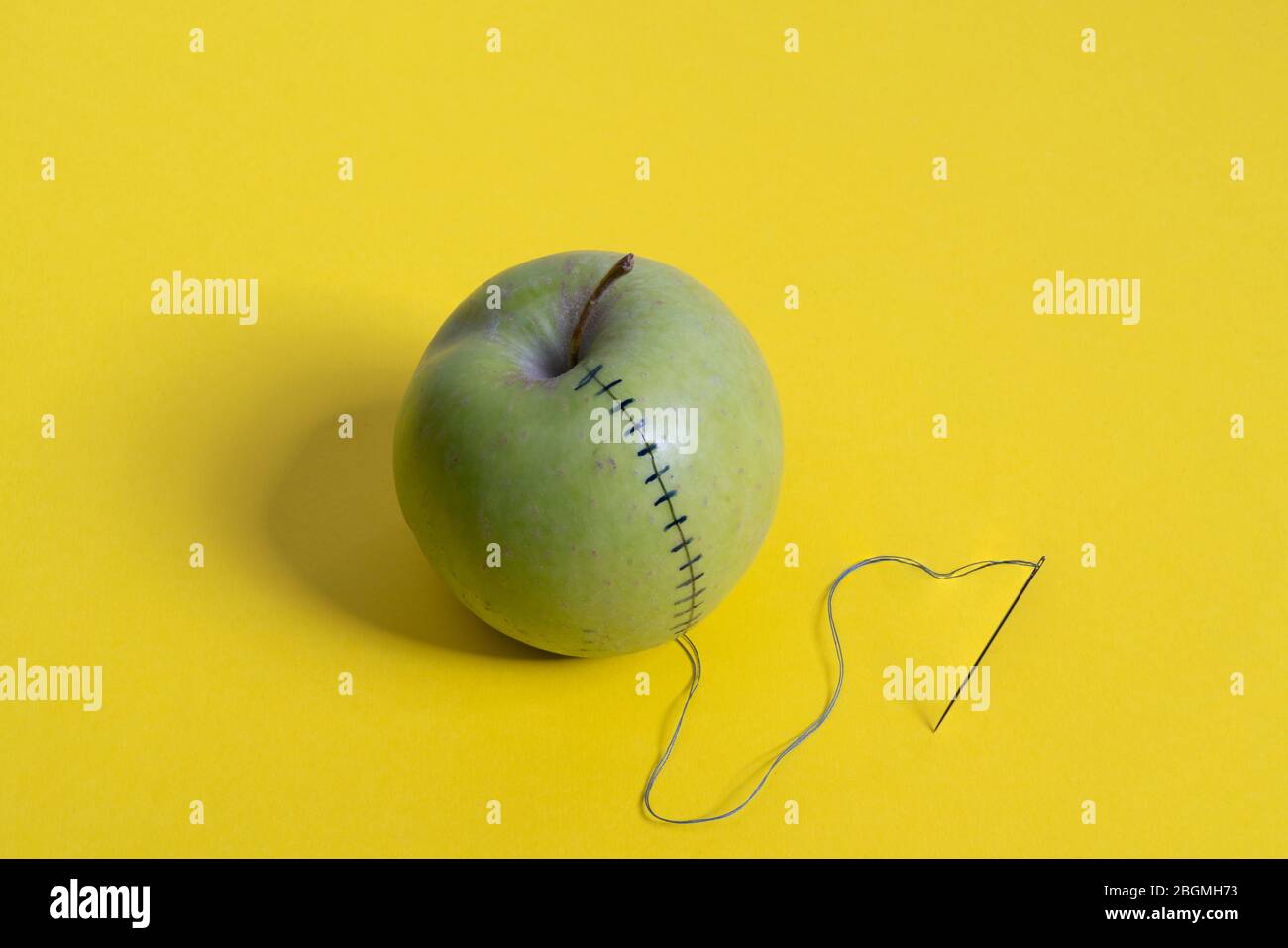 Ein Apfel mit Faden und Nadel genäht Stockfoto