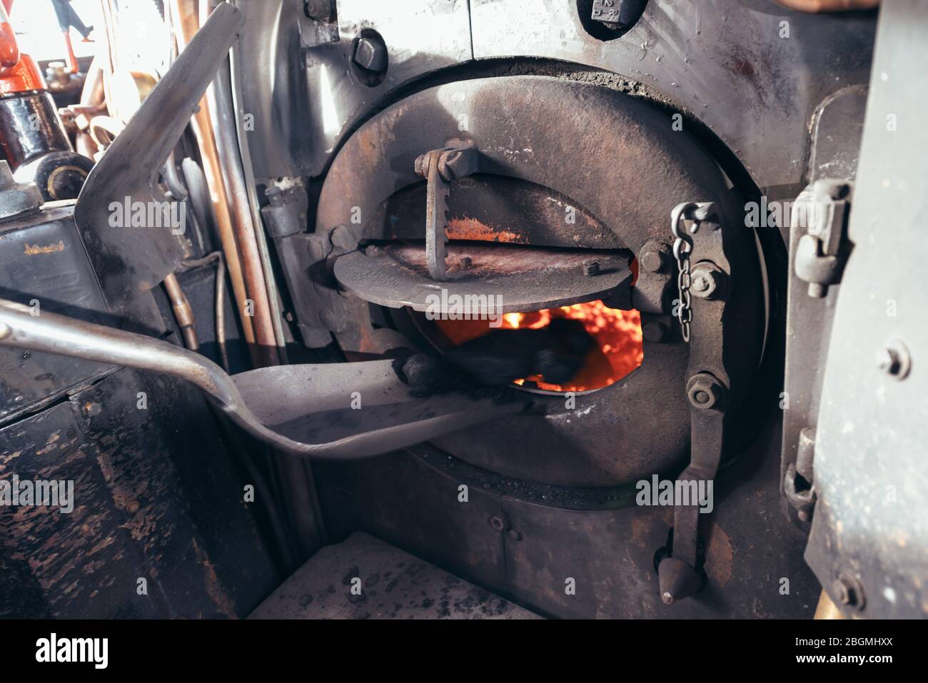 Eine geschwärzte, schmutzige Schaufel, die Kohle in die Feuerstelle bringt, die in der britischen Dampflokomotive Sir Nigel Gresley (LNER Klasse A4 Pacific 4498) in der Neubrücke arbeitet Stockfoto