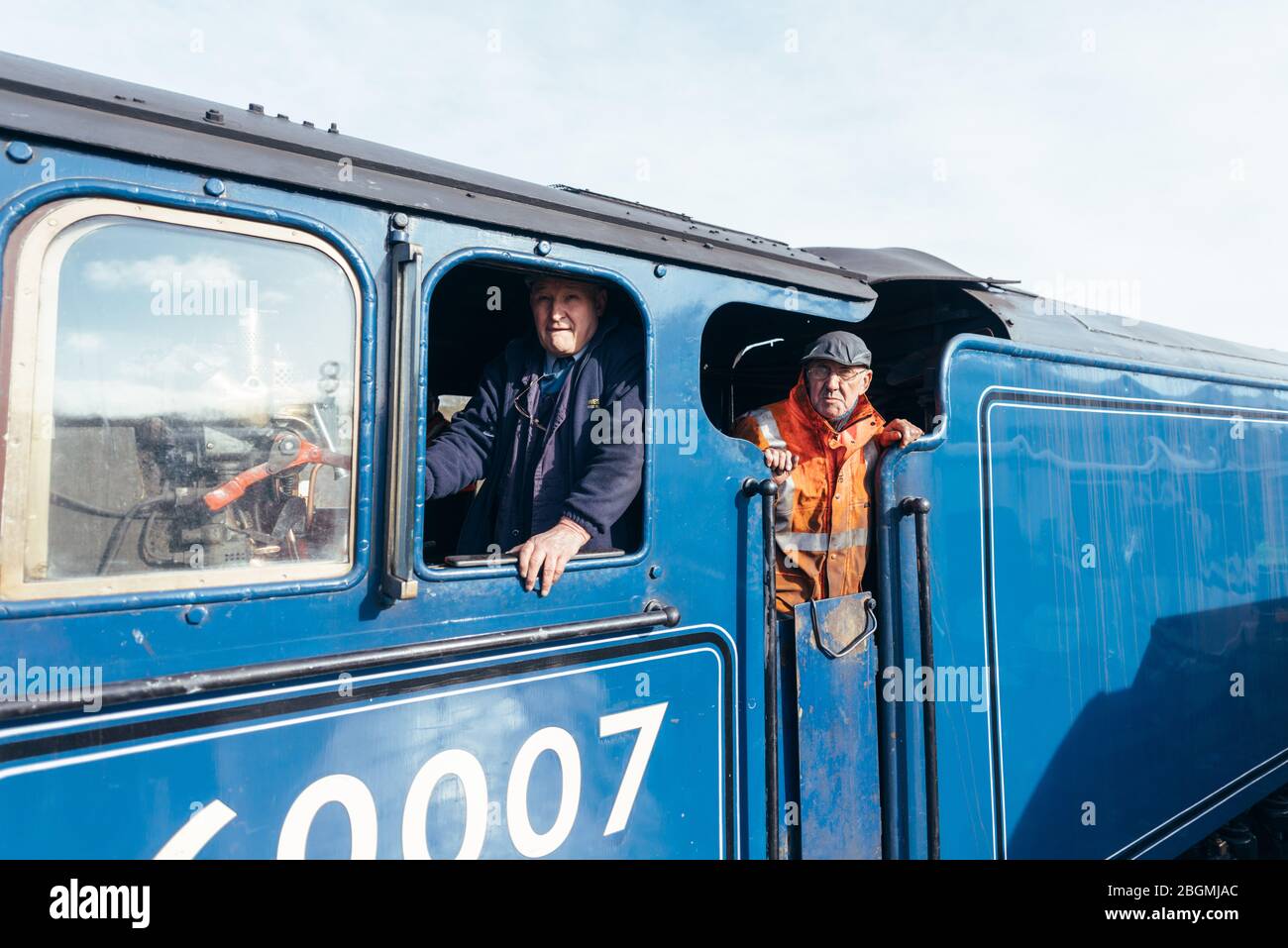 Zwei Männer, die aus der fahrkabinenbetriebenen britischen Dampflokomotive, der Sir Nigel Gresley (LNER Klasse A4 Pacific 4498), in British Railways (BR) blau schauen Stockfoto