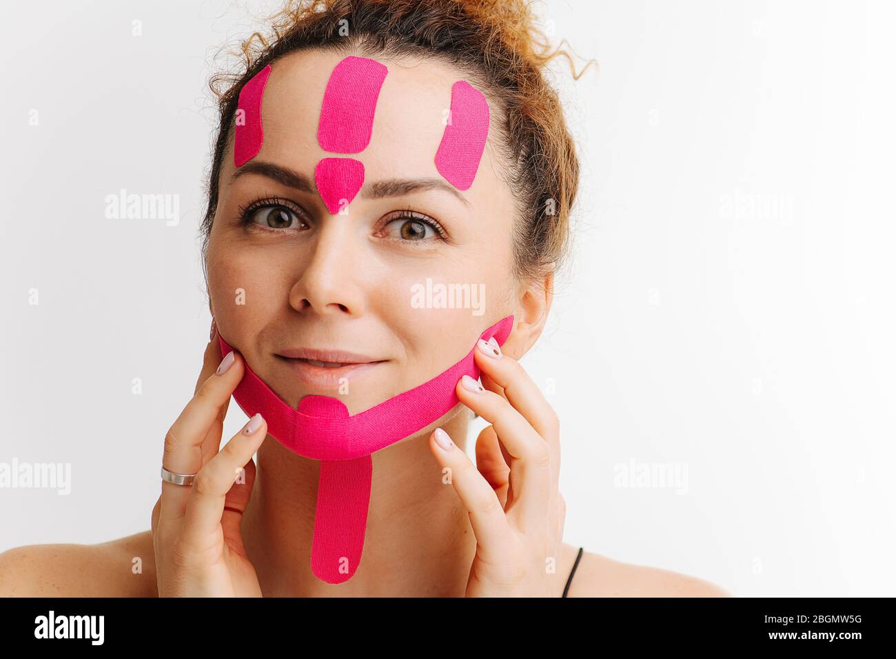 Glückliche Frau mit kosmetischen Klebeband auf ihrem Gesicht verlassen auf es Effekte, berühren Gesicht Stockfoto