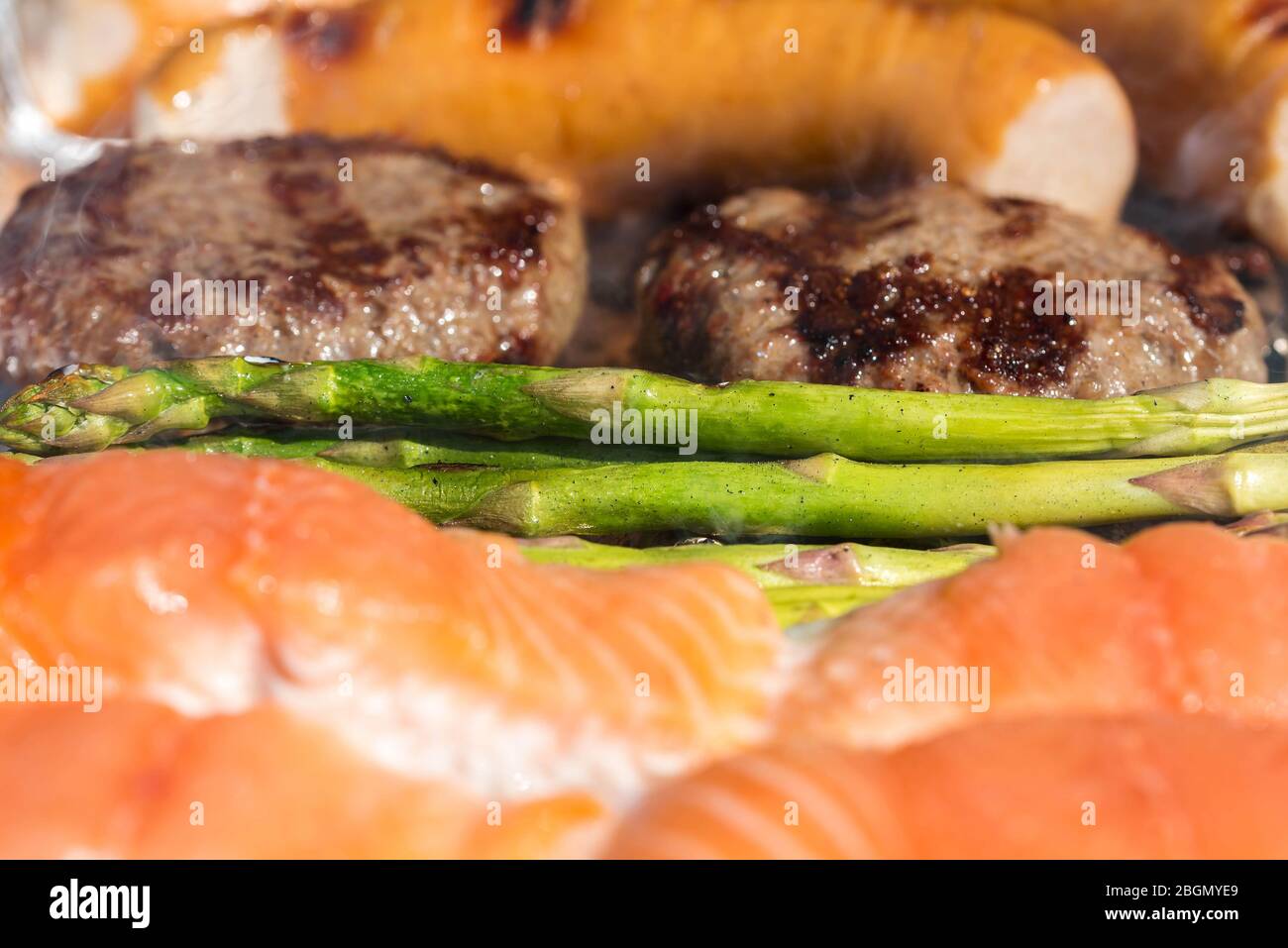 Gegrillte Paprika, Spargel, Würstchen, Burger, gegrillter Fisch. Rosa Lachs, grüner Spargel über Feuer und Rauch. Barbecue im Sommer. Freizeit und f Stockfoto