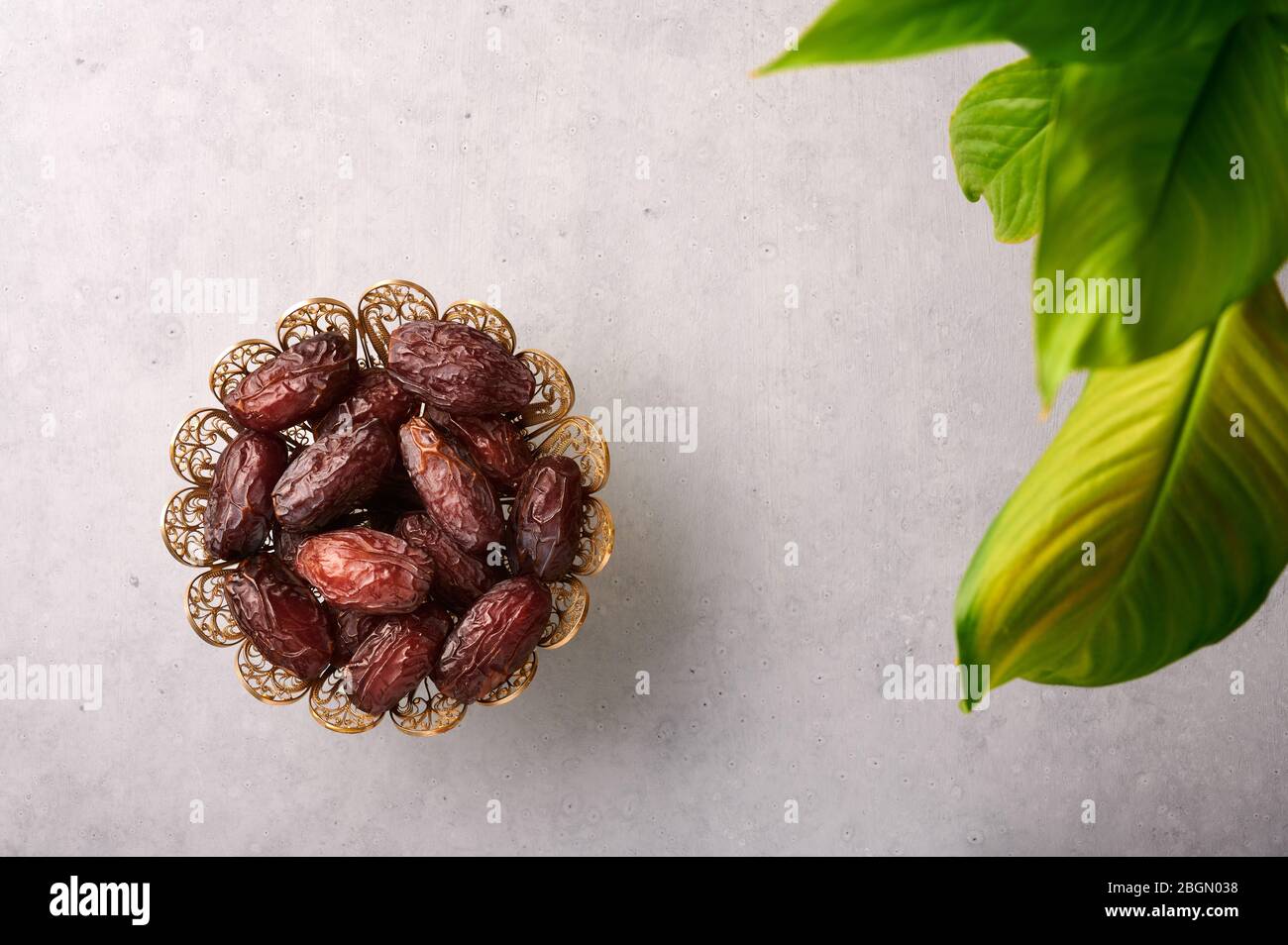 Dattieren Sie Früchte oder Kurma in der Bronzetafel auf grauem Betongrund. Datteln ist Ramadan Essen. Ramazan Iftar-Essen. Stockfoto